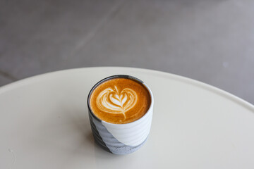 Closeup image of a woman holding a white cup of coffee with latte art