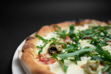 closeup of seafood pizza with shrimp, mussels and arugula on black background