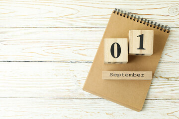 Notebook and wooden calendar with September 1 on white wooden background