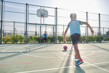 Two brothers playing football, one of them has a leg prosthesis and the other is kicking a penalty. Siblings playing sports together.