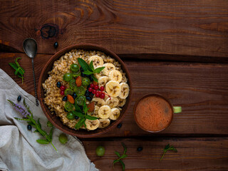 Wholegrain Oatmeal porridge bowl with fresh berries, fruits, nuts mint leaves tea cup. Healthy food oat meal morning breakfast top view. Whole grain cereal gooseberry currant banana on wooden table.