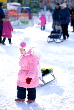 Little girl pulling a sled in the snow