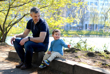 Fototapeta premium Father and son have a rest in the park near the river