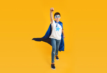 Teenage boy in superhero costume on yellow background © New Africa