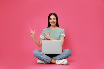 Naklejka premium Young woman with modern laptop on pink background