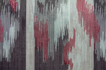 Abstract fabric pattern with embroidery on gray and white with red fabric. Background texture for the design.