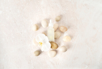 Beautiful spa composition of natural cosmetics with sea pebbles and white orchid flower on natural pink marble background. Flat lay style. Copy space.