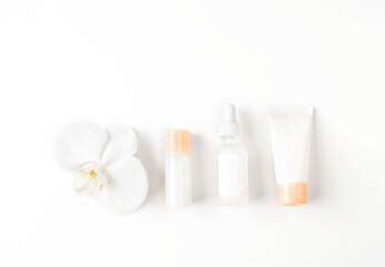 Fototapeta na wymiar Beautiful spa composition of natural cosmetics mockup bottles with orchid flower lined up on white background. Top view. Flat lay style. Copy space.