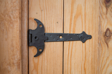 New black decorative metal hinge on wooden door