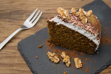 Closeup of a portion of a carrot cake with pieces of walnut