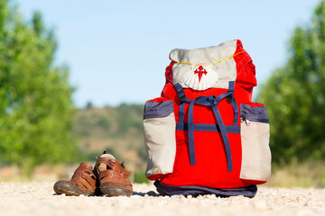 Way of St James , Camino de Santiago ,scallop shell on backpack  on dirt road with old sandals  to...