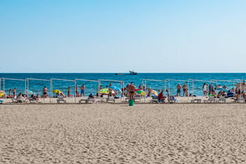 Zaliznyi Port, Ukraine - July 23, 2020: Beach coastline in the resort village of Zalizny Port. People are resting on white sand against a background of blue water