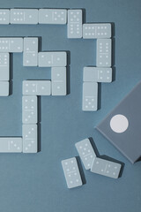 Light Blue wood domino pieces on light blue background. Leisure games concept.