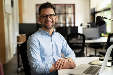 Obraz premium Young businessman using laptop in his office. Handsome man working on laptop..