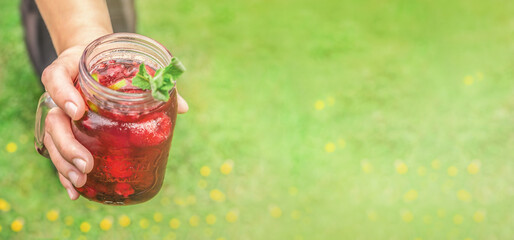 A person offering a refreshing summer drink. Wide screen with text space on green background