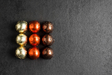 Chocolate candies wrapped in multicolored foil on black background