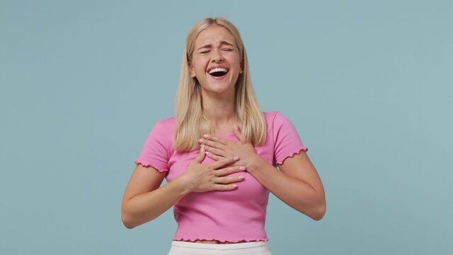 Excited cheerful young blonde woman 20s wears pink t-shirt look camera laugh smiling watch comedy movie point index finger on you isolated on pastel plain light blue color background studio portrait