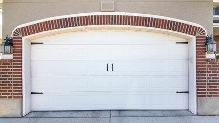 Pano Closed carriage style white garage door of a house with bricks