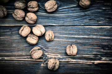 Whole walnuts lie on a rustic old wooden table. Harvest walnuts.