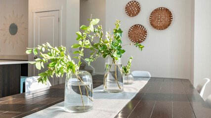 Pano Wooden plank table top at dining area with centerpiece cloth and water plants in a jar