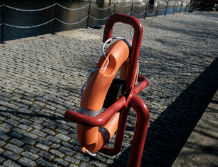 Orange life buoy on a holder at Shadwell basin, London. Water safety equipment