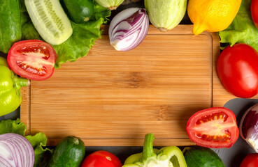 Fresh whole and chopped raw vegetables lie around a cutting board.