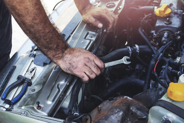 A locksmith repairs a car with a wrench. Repair work