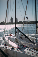 Sailing sport yachts moored at the pier on a sunny day. Many yachts with lowered sails stand near the pier