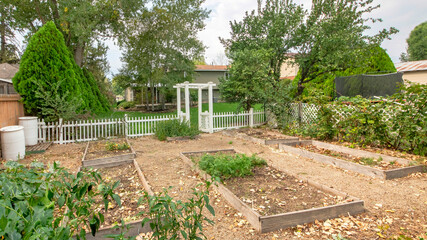 Pano Backyard of a property with a garden in it and a white fence.