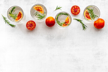 Red orange lemonade in glasses with ice and rosemary
