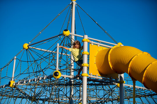 Child On Slide Playground Area. Kid Boy Climbed On Top Of The Rope Web, Kids Growth Concept.