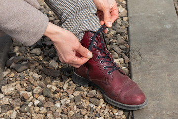 women's hands lace up a crimson shoe close up