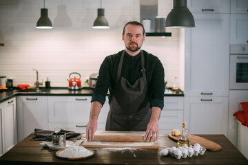 A male chef prepares noodles at home in the kitchen.