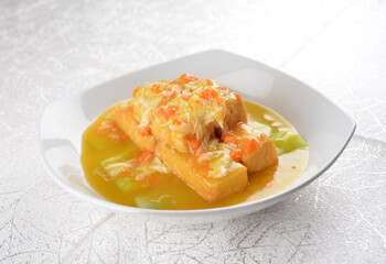 Deep fried bean curd tofu with luffa melon in yellow chicken stock sauce and crab meat on white background Asia halal menu
