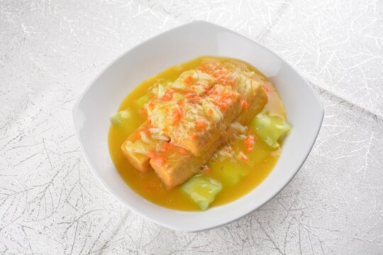 Deep fried bean curd tofu with luffa melon in yellow chicken stock sauce and crab meat on white background Asia halal menu
