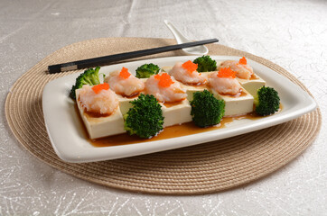 steamed bean curd tofu with minced prawn seafood on top and broccoli vegetables in dark soy sauce on white background Asia appetiser halal menu