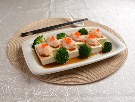 steamed bean curd tofu with minced prawn seafood on top and broccoli vegetables in dark soy sauce on white background Asia appetiser halal menu