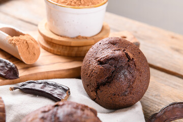 Chocolate carob cupcake cooking with carob powder and dried carob pods and carob powder in a bowl over wooden background. Organic healthy sweet food for vegan vegetarian food and drinks, close up