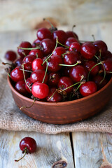 Selective focus. Ripe juicy cherries in a bowl on a wooden surface. Organic cherry harvest.