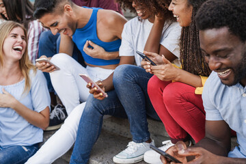 Happy young people using smartphones outdoor - Diversity and millennial generation concept - Focus...