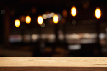 image of wooden table in front of abstract blurred background of lights of restaurant bar cafe