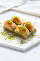 Baklava with pistachio on a white wooden background. Baklava on a marble floor