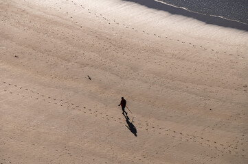 A silhouette of a man during a summer day walking alone in the beach