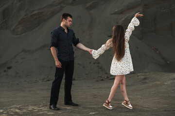 Happy couple dancing outdoors at summertime on gray sand background