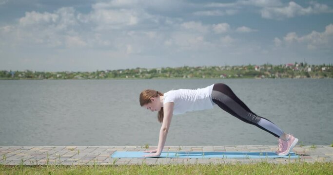 Sporty young woman practicing yoga near river