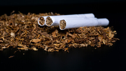 some cigarette and Pile of tobacco on a black background