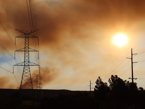 Large Overland Power Lines Leading Toward The Blue Mountains With Bush Fire Smoke Haze Across The Setting Sun.