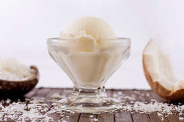 Coconut ice cream in a bowl with grated coconut decoration in the background