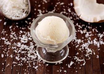 Coconut ice cream in a bowl with grated coconut decoration in the background