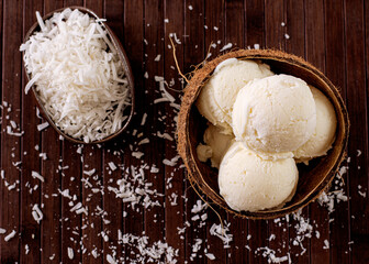 Coconut ice cream in natural coconut shell with grated coconut decoration in the background